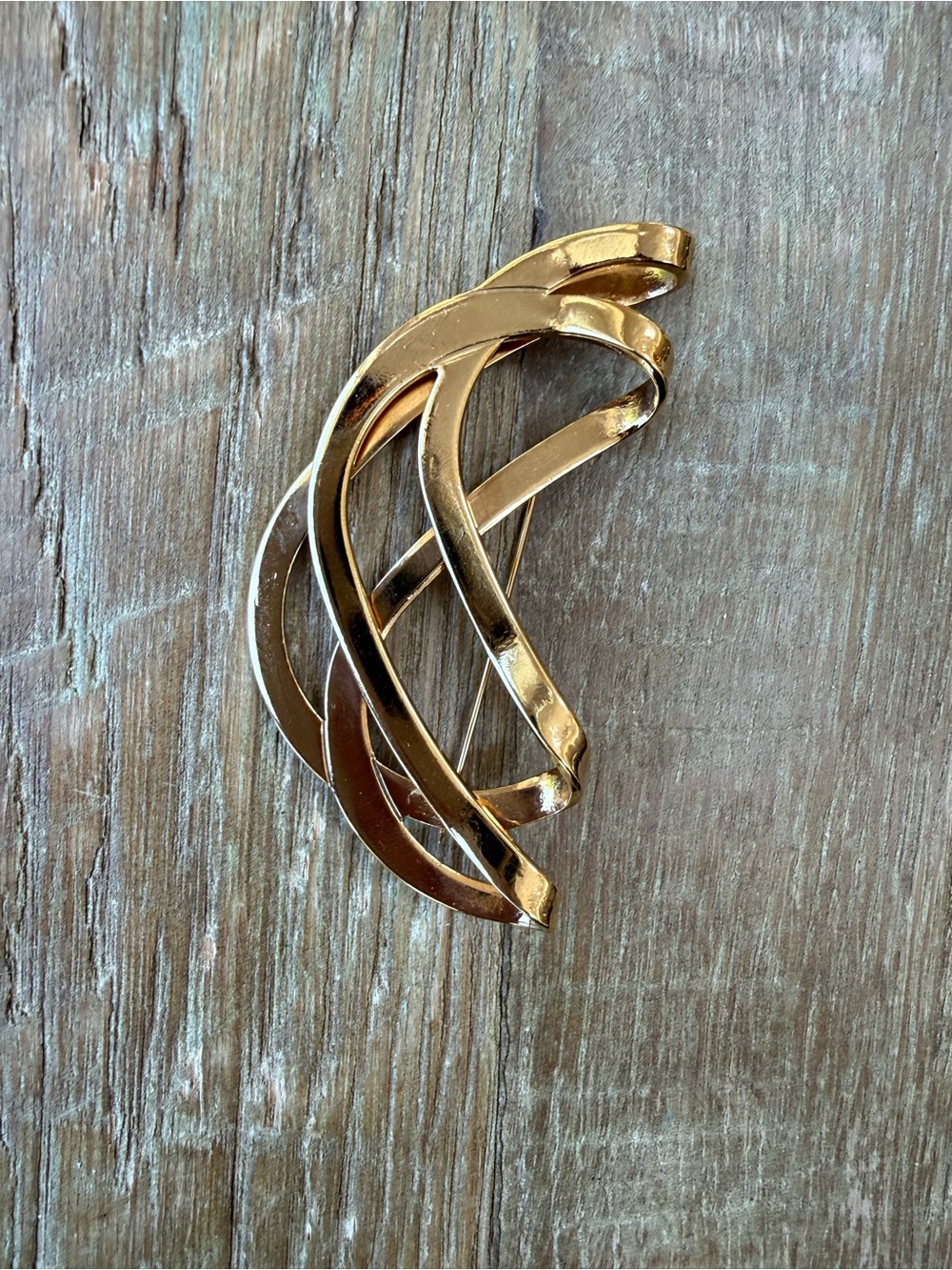 Gold tone abstract brooch with a swirl